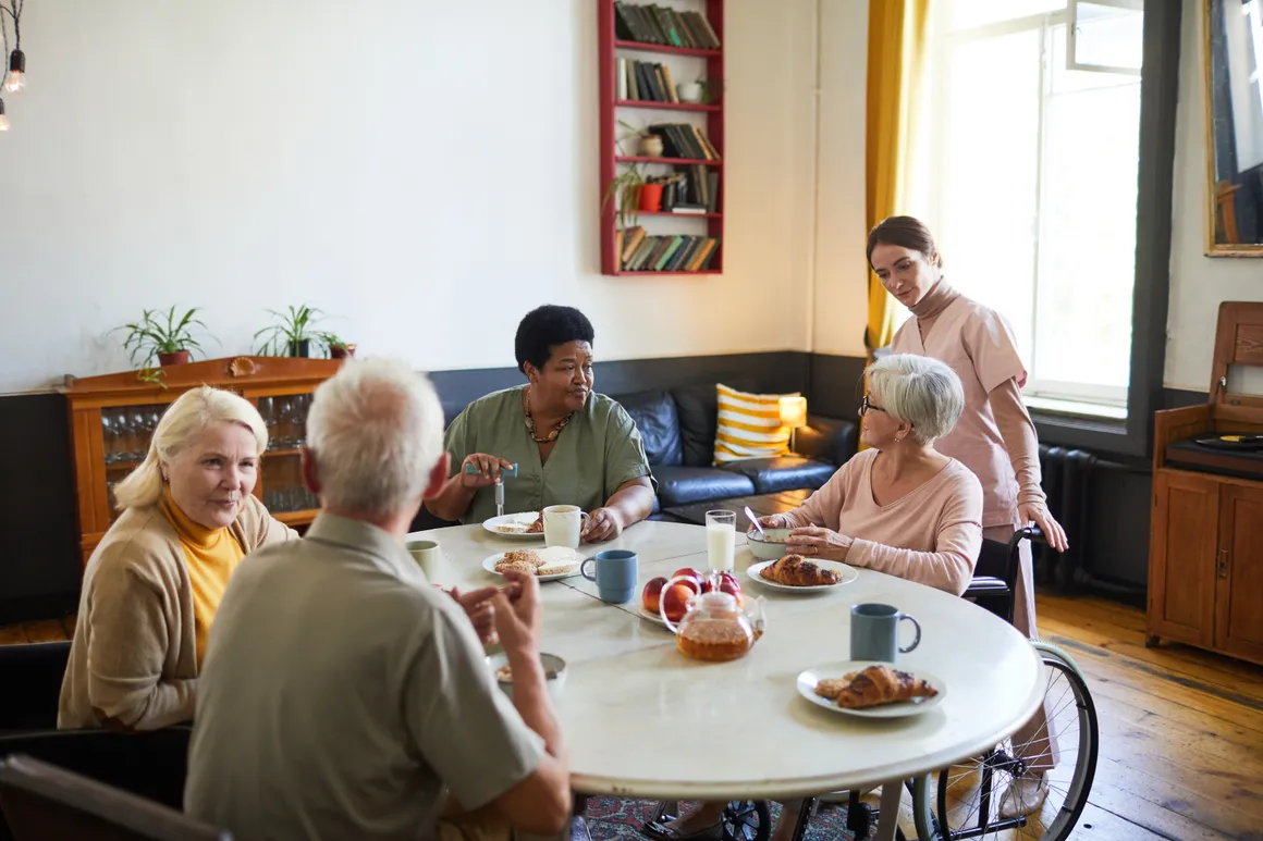 Residents talking over coffee in a community dining room, staff nearby