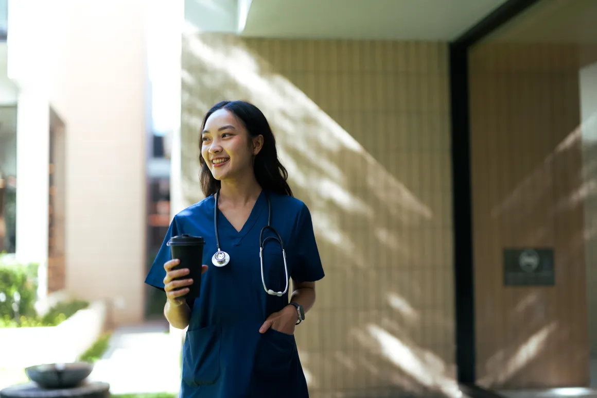 A caregiver in navy scrubs walking out of a community entrance