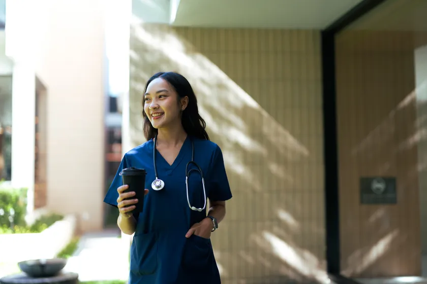 A caregiver in navy scrubs outside a community entrance