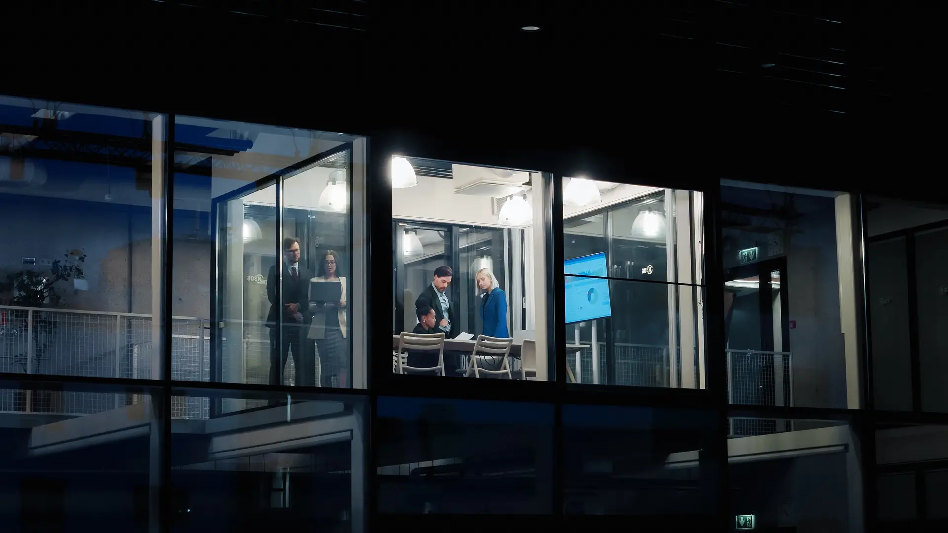 A team reviewing screens in a glass office at night