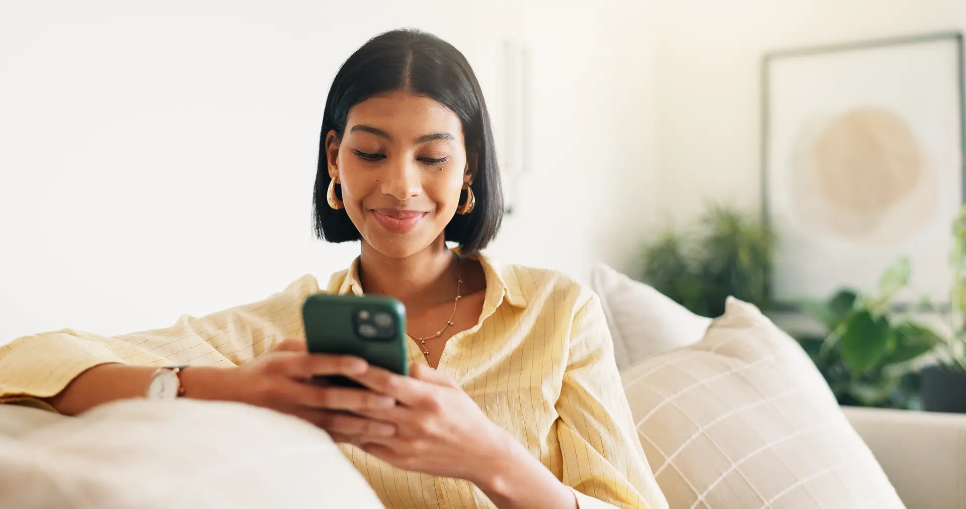 A woman on a sofa reading a message on her phone