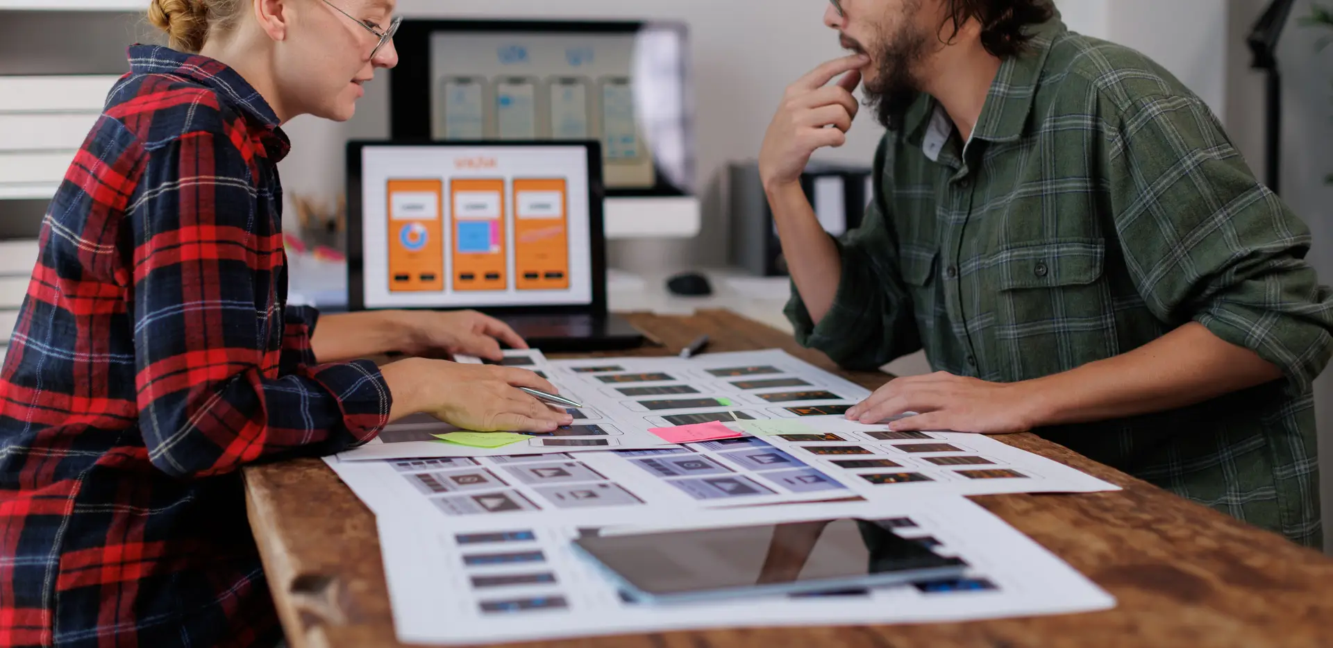 Two designers reviewing website page mockups at a desk